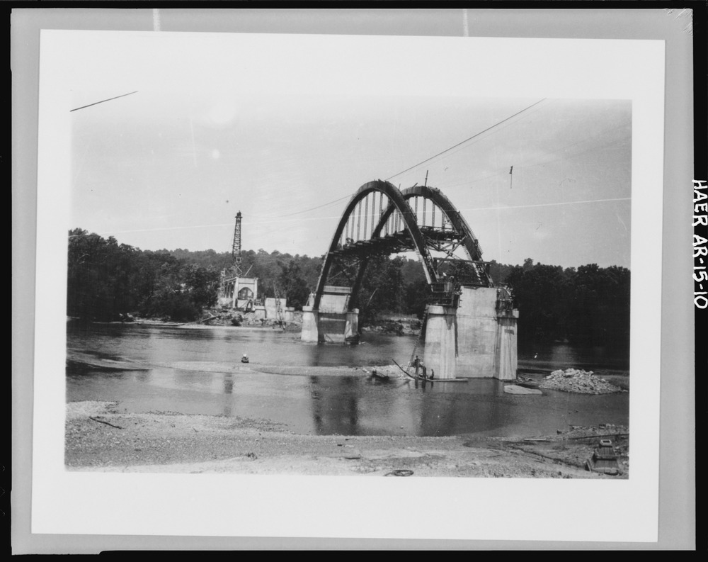 View of bridge under construction, showing central arch and piers, with cableway above and tower on background - Cotter Bridge, spanning White River at U.S. Highway 62, Cotter, Baxter County, AR.