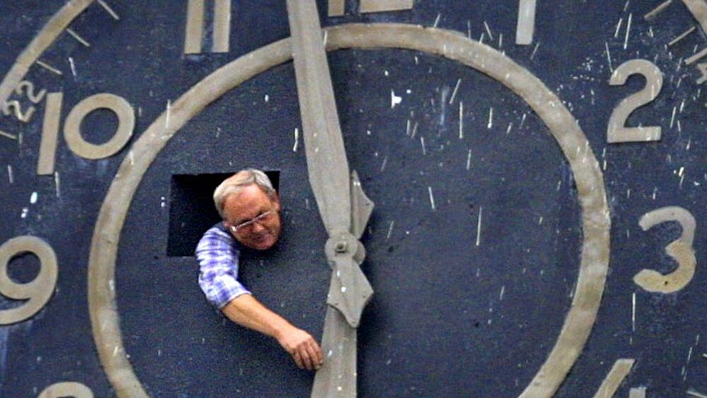 man changing a gigantic clock face
