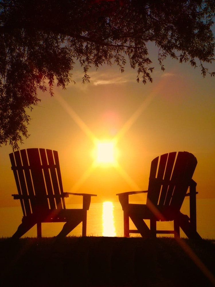 2 empty chairs facing the sunset