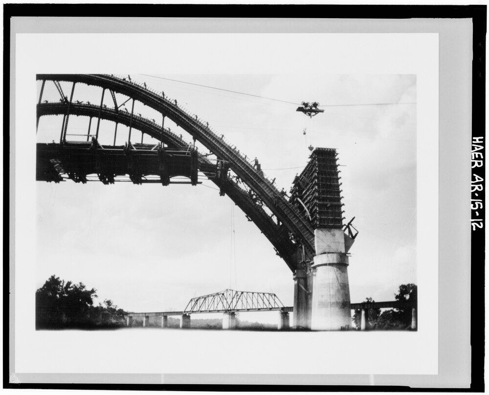 View, looking North, showing cableway and tram above an arch under construction, with railroad bridge in background - Cotter Bridge, spanning White River at Highway 62, Cotter, Baxter County, AR.