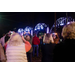 Attendees stand together, taking photos of the bridge as it lights up.